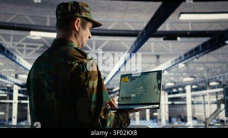 Military technician in a military data center monitors satellite coordinates with radar software, scanning aerial activity for defense operations. Stock Photo