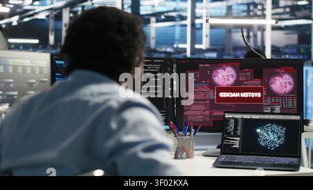 Man using a wheelchair in a data center reacts to a malware alert on a computer, securing server equipment and protecting confidential data. Stock Photo