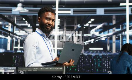 Data center administrator uses laptop node tree software to review analytics and identify equipment issues. Stock Photo