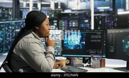 Server facility technical specialist applying AI ML models to set up hardware. African American woman works on AI programming tools in data center, optimizing system. Stock Photo