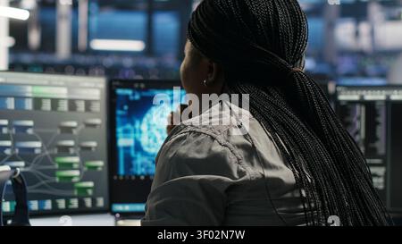 Server facility software engineer applying AI ML models to set up hardware. IT professional works on AI programming tools in server environment, optimizing system. Stock Photo