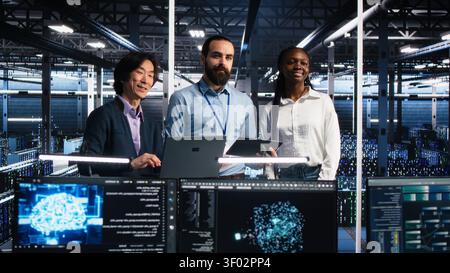 Happy high tech server room team members collaborating on neural network software development. Stock Photo