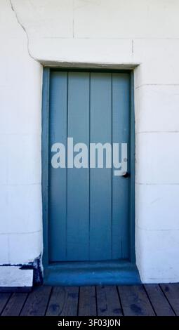 Minimalist Blue Wooden Door in White Stucco Wall Stock Photo