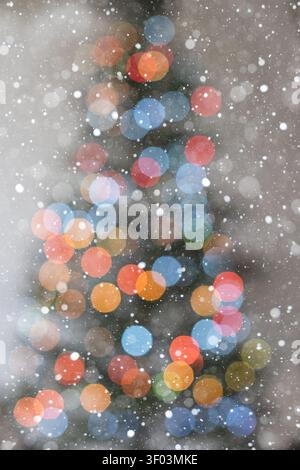 Minimalistic vertical holiday background with cool Christmas tree bokeh lights on a white backdrop. Soft snowfall creates a fresh winter atmosphere su Stock Photo