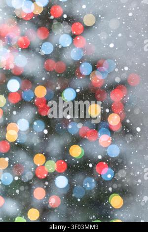 Vertical festive background with colorful Christmas tree bokeh lights on a clean white background. The visible outline of part of the tree and softly Stock Photo