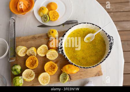 A top-down view of a citrus juicer on a kitchen counter, showcasing the fresh preparation of squeezed citrus juice in a ceramic bowl. The scene is set in a natural light environment, idealy. Stock Photo
