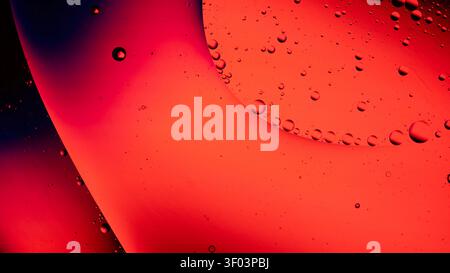 Closeup of an abstract macro background featuring warm orange and red tones with glossy liquid droplets scattered across a curved surface Stock Photo