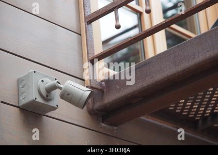 Wall-mounted security camera near wooden balcony Stock Photo