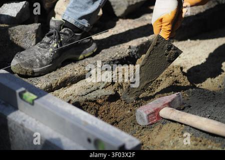 Worker lays concrete in construction area during daytime Stock Photo