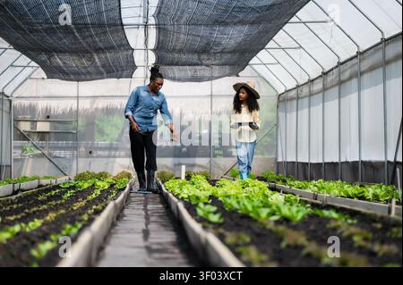 Mother teaching daughter gardening in greenhouse, Learn practical skills with mother while using modern technology in tablet step info smart farmer ne Stock Photo