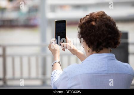 Senior woman using smartphone to take photo, rear view Stock Photo