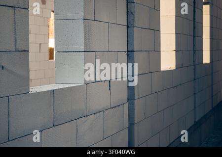 Unfinished concrete block wall with rectangular window openings at an indoor construction site, showcasing masonry work, raw materials and industrial Stock Photo