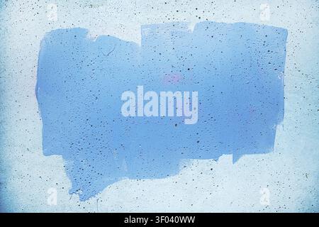 A rectangular swath of blue paint on a rough concrete wall, showing drips, speckled flecks and subtle gradients that form an abstract, grunge-style ba Stock Photo
