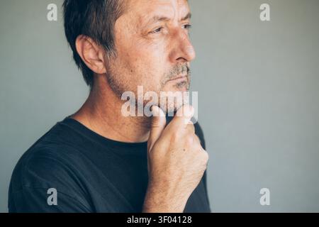 Authentic portrait of a middle-aged man with a serious expression against a neutral background. Mental wellbeing, resilience and modern masculinity co Stock Photo