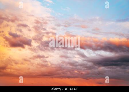 Dramatic sunset sky filled with colorful clouds illuminated by warm evening light. Atmospheric nature background with vibrant orange, pink and blue to Stock Photo