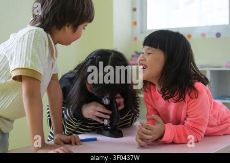 The students are having fun looking through the microscope. Stock Photo