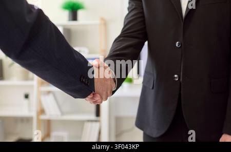Businessmen shake hands in modern office after negotiation and partnership deal Stock Photo