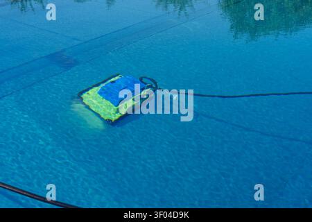 Robotic pool cleaner underwater in blue swimming pool Stock Photo