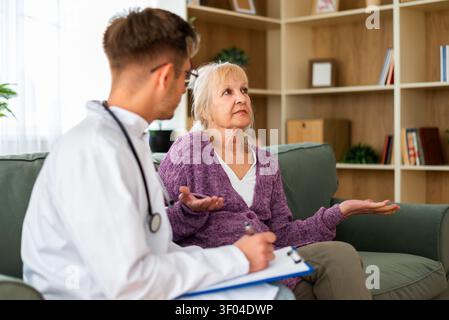 A healthcare professional carefully documents an elderly patient's concerns as she discusses her health issues during an in-home medical appointment. Stock Photo