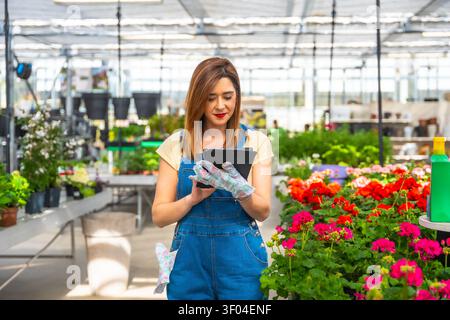 Woman managing greenhouse inventory with digital tablet Stock Photo