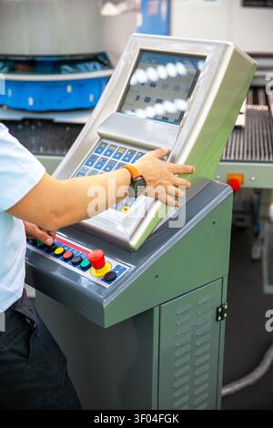 Industrial operator controlling CNC punching machine touchscreen panel in modern metal fabrication factory Stock Photo