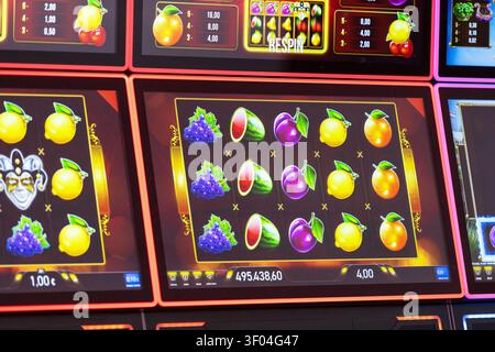 Casino slot machine display screen showing glowing rows of animated fruit symbols during a gaming session Stock Photo