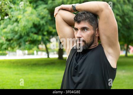 Athletic Man Stretching Triceps Before an Outdoor Workout in a Park Stock Photo