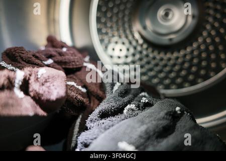 A clothes inside washing machine drum ready for washing, showing fabric texture and metal interior with soft lighting creating cozy household chore at Stock Photo