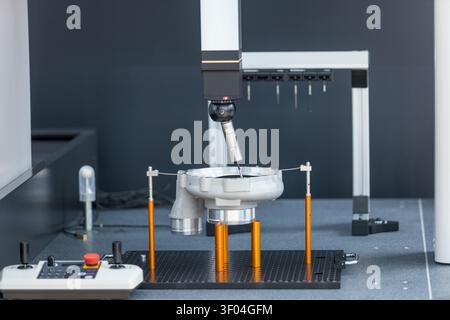 Motorized indexing probe head performing high-precision dimensional inspection of machined metal component on coordinate measuring machine in industri Stock Photo