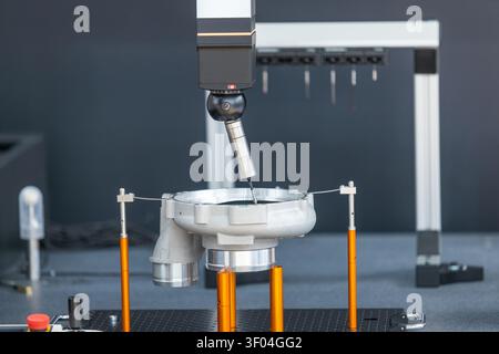 Motorized indexing probe head performing high-precision dimensional inspection of machined metal component on coordinate measuring machine in industri Stock Photo