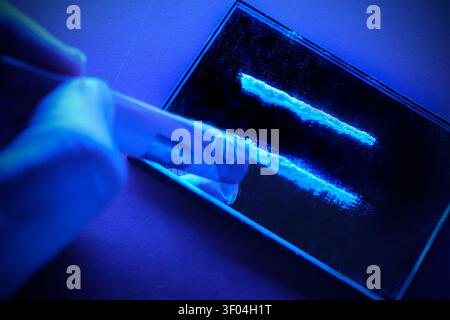 A close-up of two lines of cocaine or a powdered drug on a reflective surface, whilst a person holds a rolled-up euro banknote ready for consumption. Stock Photo