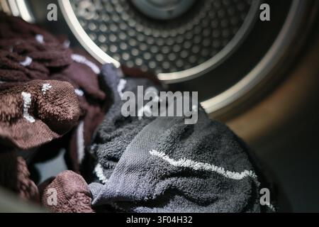 A laundry inside dryer with dark colored towels drying under warm light, showing texture and fabric details in household chore setting Stock Photo