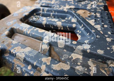 A mud splattered on textured black plastic surface with geometric shapes, showing dirt and outdoor wear on rugged equipment Stock Photo