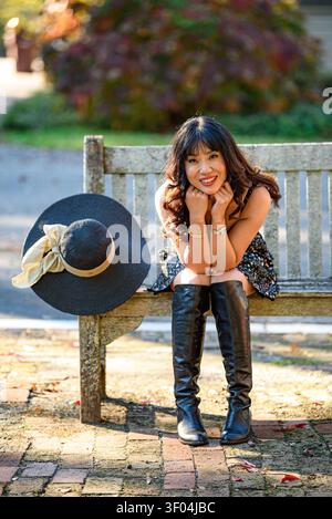 A Smiling Chinese woman sitting on a bench Stock Photo
