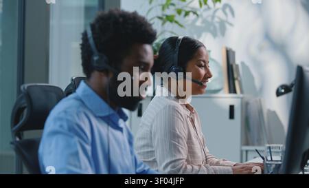 Two serious multiracial business colleagues working in call center consulting clients talking online consultation in agency. Team multiethnic Stock Photo