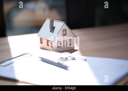 Real Estate Concept House Model on Desk with Important Document Stock Photo
