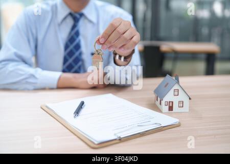 Real Estate Agent Presenting House Keys with Contract and Model Stock Photo