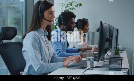 Three multiethnic business colleagues call center managers team consulting clients talking distant customer help support service in office. Smiling Stock Photo