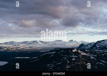 Majestic snow capped mountains under dramatic clouds Stock Photo