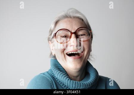 Joyful senior woman with glasses laughing loudly Stock Photo