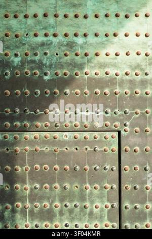 Detailed full-frame view of a historic green metal gate studded with rows of round brass rivets, Kyoto, Japan Stock Photo