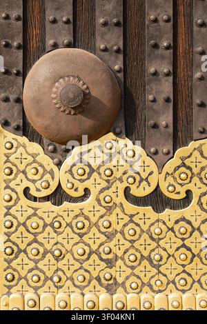 Extreme close-up of a massive ornate brass door handle and decorative gold flower pattern sheeting on a wooden gate, Kyoto, Japan Stock Photo
