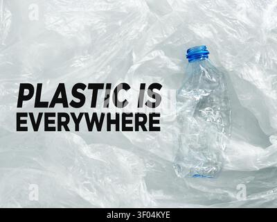 Crushed plastic bottle on plastic bags background emphasizing pollution, recycling, sustainability, and environmental concern Stock Photo