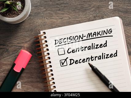 Notebook top view with check boxes for centralized or decentralized decision making, selecting the decentralized option with a marker Stock Photo
