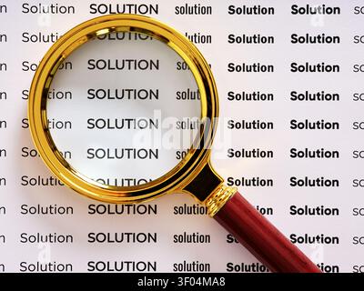 Magnifying glass focusing on SOLUTION text, symbolizing searching for a solution, solution analysis or problem solving Stock Photo