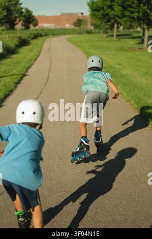 Two boys rollerblading on a path on a sunny day Stock Photo