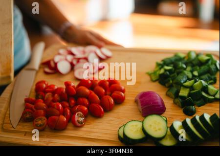 Person preparing fresh vegetables on a cutting board in kitchen Stock Photo
