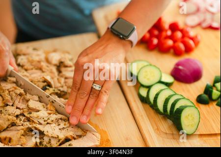 Woman slicing grilled chicken for a fresh salad for healthy meal Stock Photo