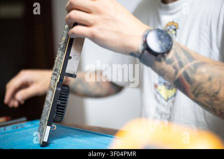 Technician works on computer hardware in a workshop during the day Stock Photo