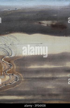 Vertical close up of a sandstone slab with multicolor bands, abstract vein like streaks on the left side, visible grain Stock Photo
